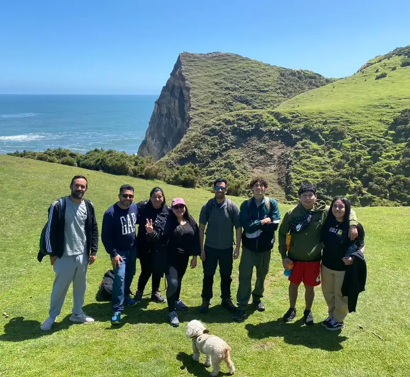 Grupo de viajeros en el campo frente a los acantilados de Cucao