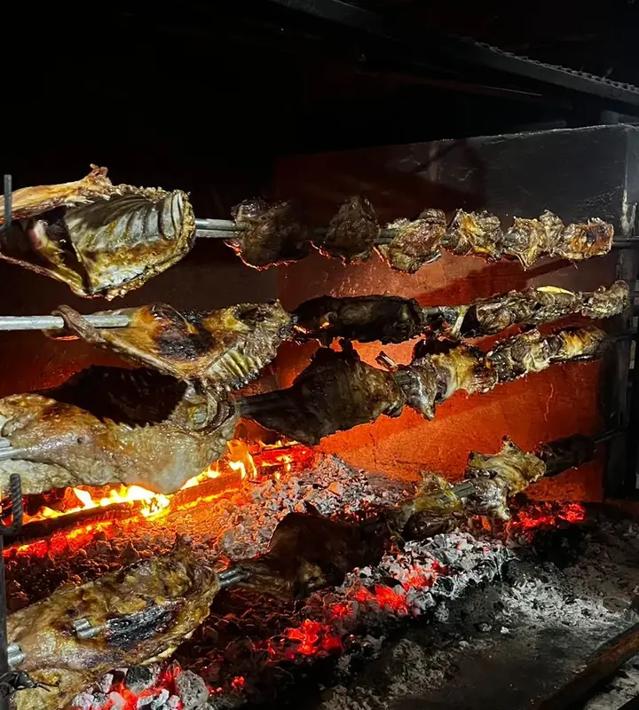 Corderos asándose al palo junto al fuego