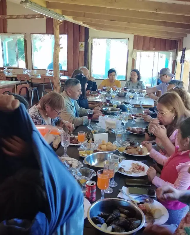 Viajeros almorzando curanto en una mesa larga