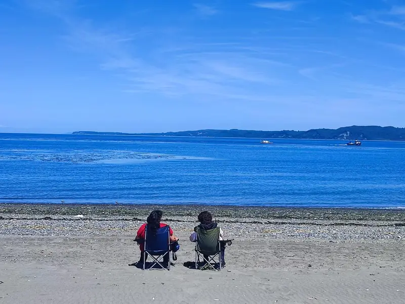 Dos viajeras sentadas en la playa de Hueñay, en Isla Lemuy
