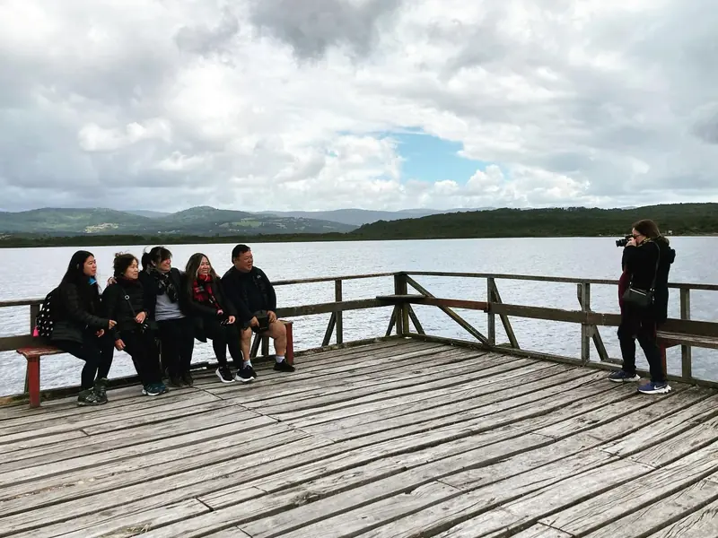 Viajeros sentados en un mirador de madera frente al lago