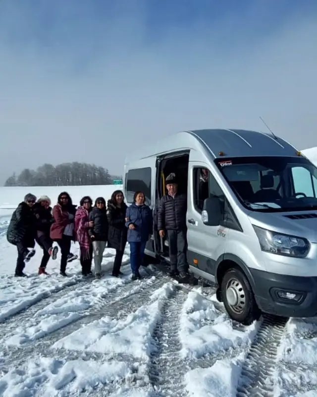 Grupo de viajeros en la nieve junto a la van, en el viaje a Bariloche