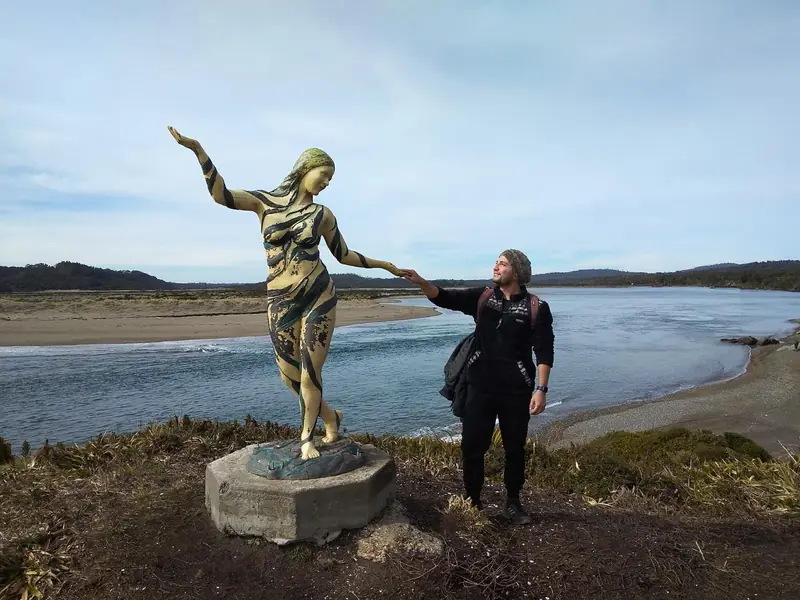 Viajera junto a la escultura de la Pincoya frente al mar