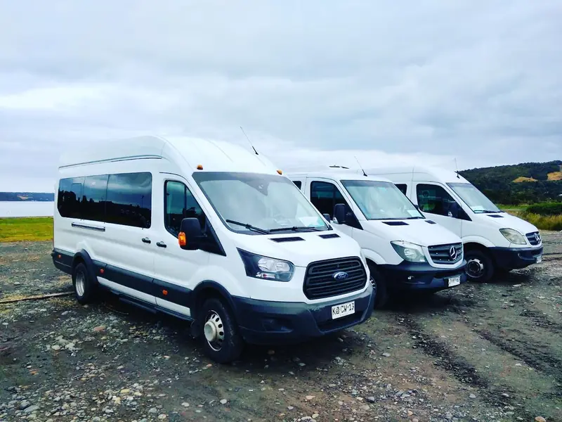 Tres vans blancas de la agencia estacionadas junto al mar